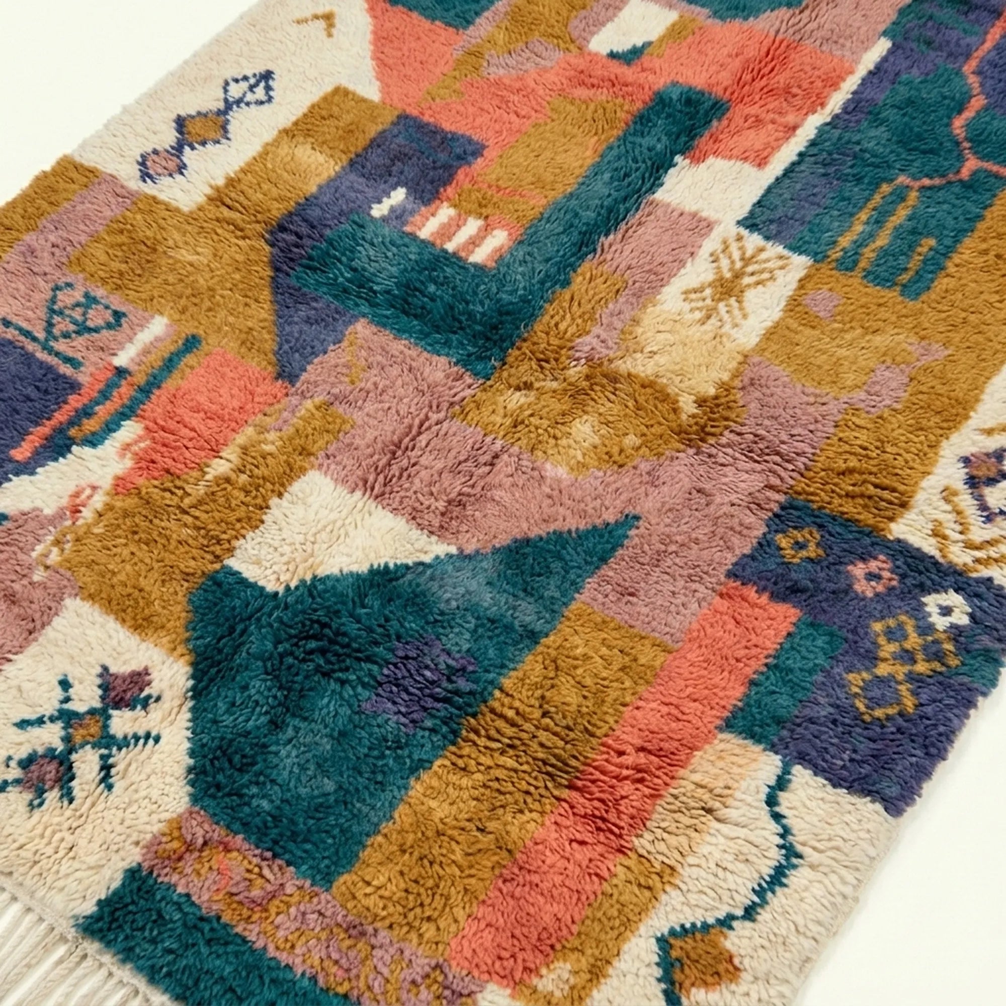 Close-up of the Tazmara Boujaad rug showing layered geometric patchwork and small woven symbols