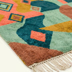 Fringe and lower-edge detail of the Tifawin Boujaad rug beside teal and coral abstract shapes
