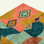 Angled close-up of a framed diamond motif on the Tifawin teal and coral Boujaad rug