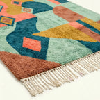 Lower edge view of Tifawin showing ochre, sage, coral and teal color blocks beside the fringe