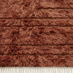 Terracotta Beni Ourain rug corner showing ivory fringe and horizontal stripe pattern