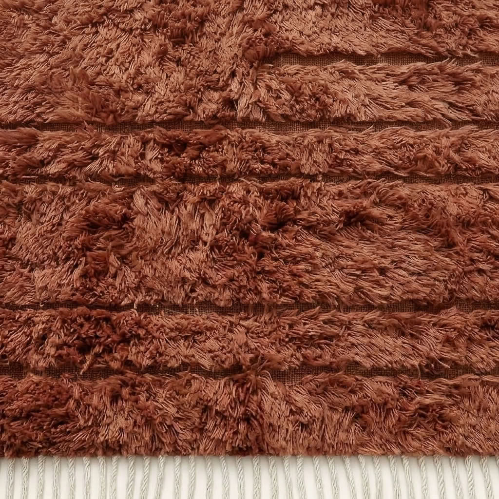 Terracotta Beni Ourain rug corner showing ivory fringe and horizontal stripe pattern