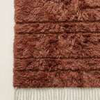 Side angle detail of terracotta Beni Ourain pile and horizontal textured stripes