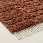 Close-up texture of terracotta Beni Ourain wool pile with organic band variation