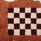 Close-up of burgundy and ivory checkerboard squares with individual knot texture visible
