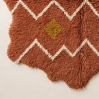 Corner fringe detail of terracotta Azilal rug with scalloped edges and golden-yellow diamond accent