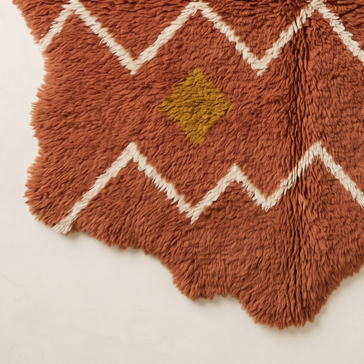 Corner fringe detail of terracotta Azilal rug with scalloped edges and golden-yellow diamond accent