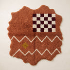 Terracotta Azilal rug with scalloped edges, featuring a burgundy and ivory checkerboard panel at the top, white zigzag bands, and a small golden-yellow diamond accent below