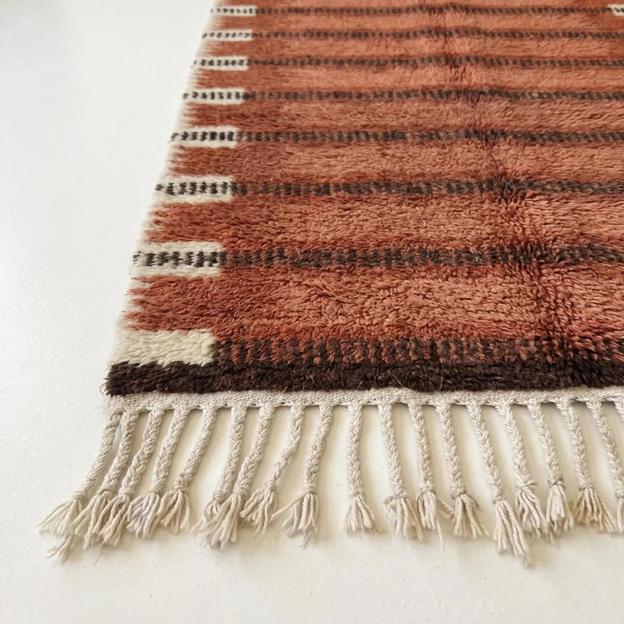 Close-up of the terracotta and charcoal horizontal band pattern on the Tiziri ivory wool rug.