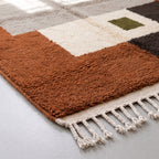 Angled detail of terracotta and ivory wool pile with fringe edge visible