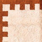 Corner detail of terracotta border with crenellated pattern and cream fringe