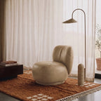 Terracotta Beni Ourain corner grid rug styled in modern minimalist living room with cream chair and arc lamp