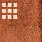 Close-up of white gridded corner design on terracotta ground showing precise handwoven pattern