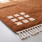 Detail of cream-white corner grid motif and fringe on terracotta Beni Ourain rug