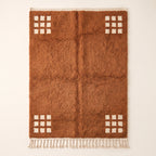 Terracotta and ivory Beni Ourain rug with cream corner grids on plain background