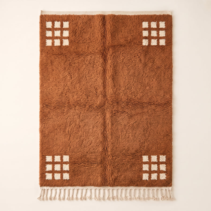Terracotta and ivory Beni Ourain rug with cream corner grids on plain background