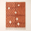 Terracotta and ivory Beni Ourain rug with diamond lattice pattern and scattered ivory diamond motifs on plain background