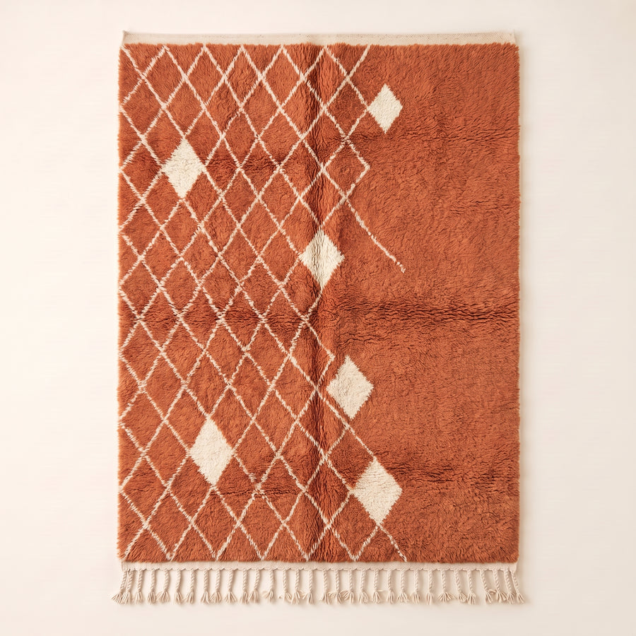 Terracotta and ivory Beni Ourain rug with diamond lattice pattern and scattered ivory diamond motifs on plain background