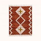 Terracotta and ivory Beni Ourain rug with diamond lattice and mustard cross design, flat lay on plain background