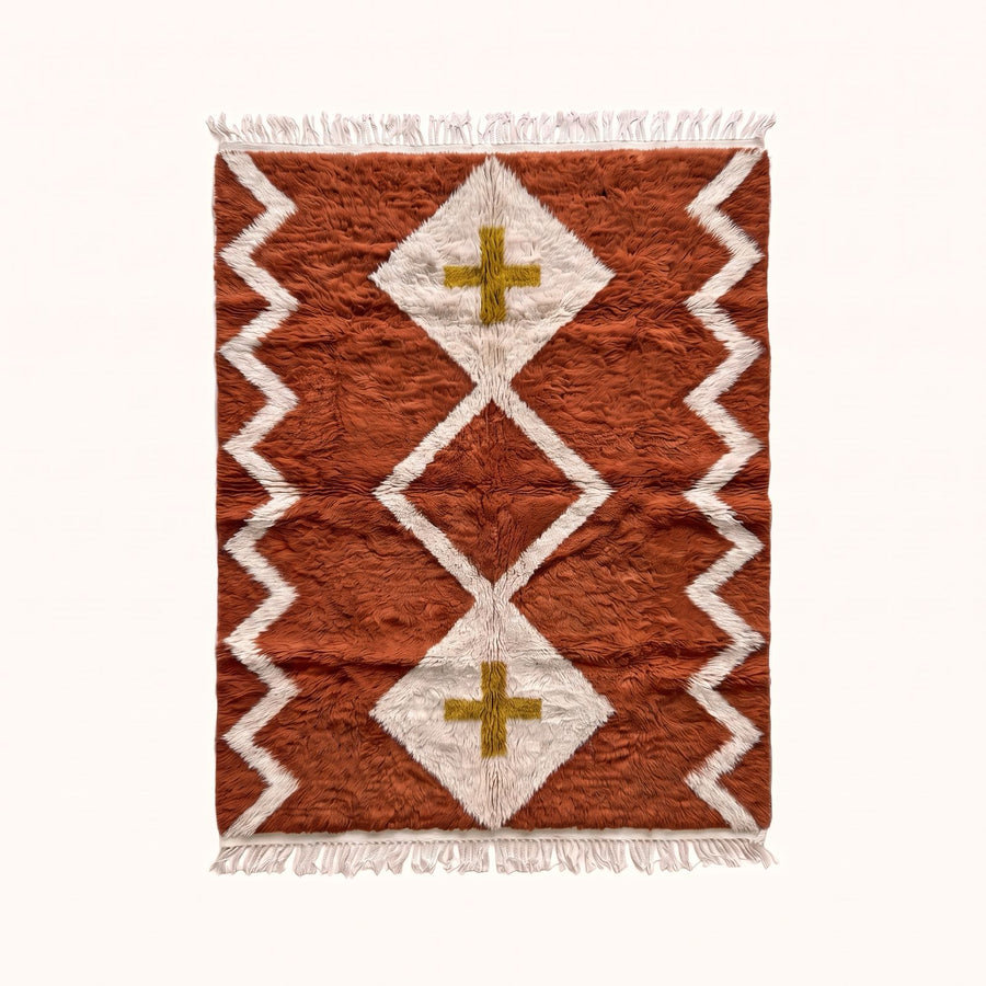 Terracotta and ivory Beni Ourain rug with diamond lattice and mustard cross design, flat lay on plain background