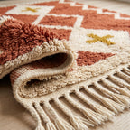 Angled detail of terracotta Beni Ourain rug pile with ivory diamond outline and mustard cross