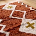 Close-up of terracotta and ivory Beni Ourain rug showing soft wool pile and diamond cross motif
