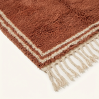 Corner and hand-tied fringe detail of the Tislit terracotta and ivory Beni Ourain rug.