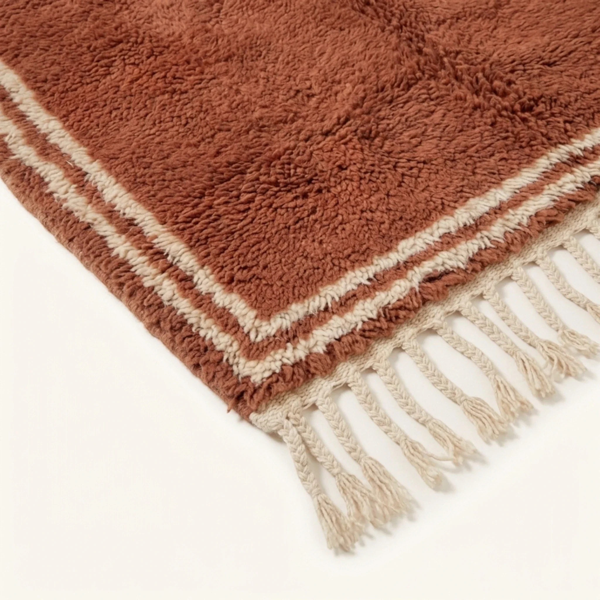 Corner and hand-tied fringe detail of the Tislit terracotta and ivory Beni Ourain rug.