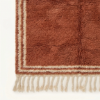 End view showing the ivory double border and terracotta field of the Tislit rug.