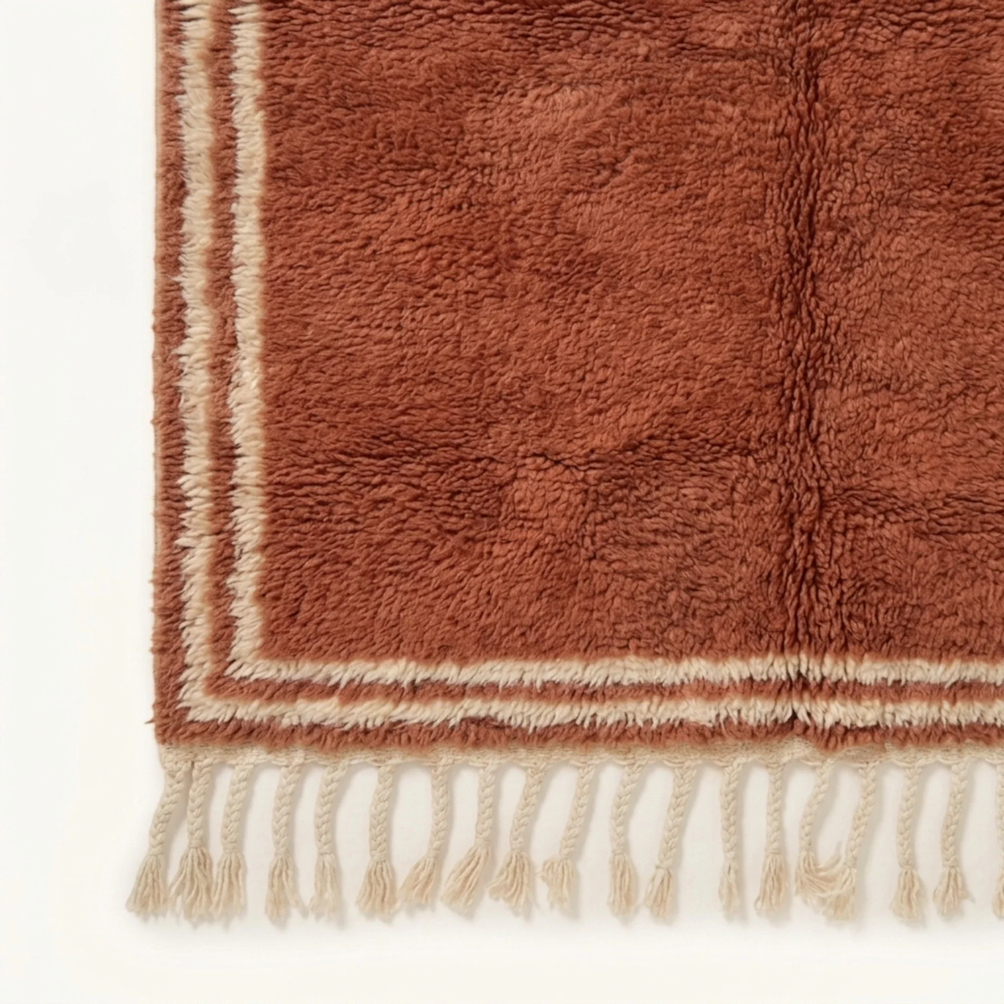 End view showing the ivory double border and terracotta field of the Tislit rug.