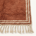 Ivory border and fringe craftsmanship on the Tislit terracotta Beni Ourain rug.