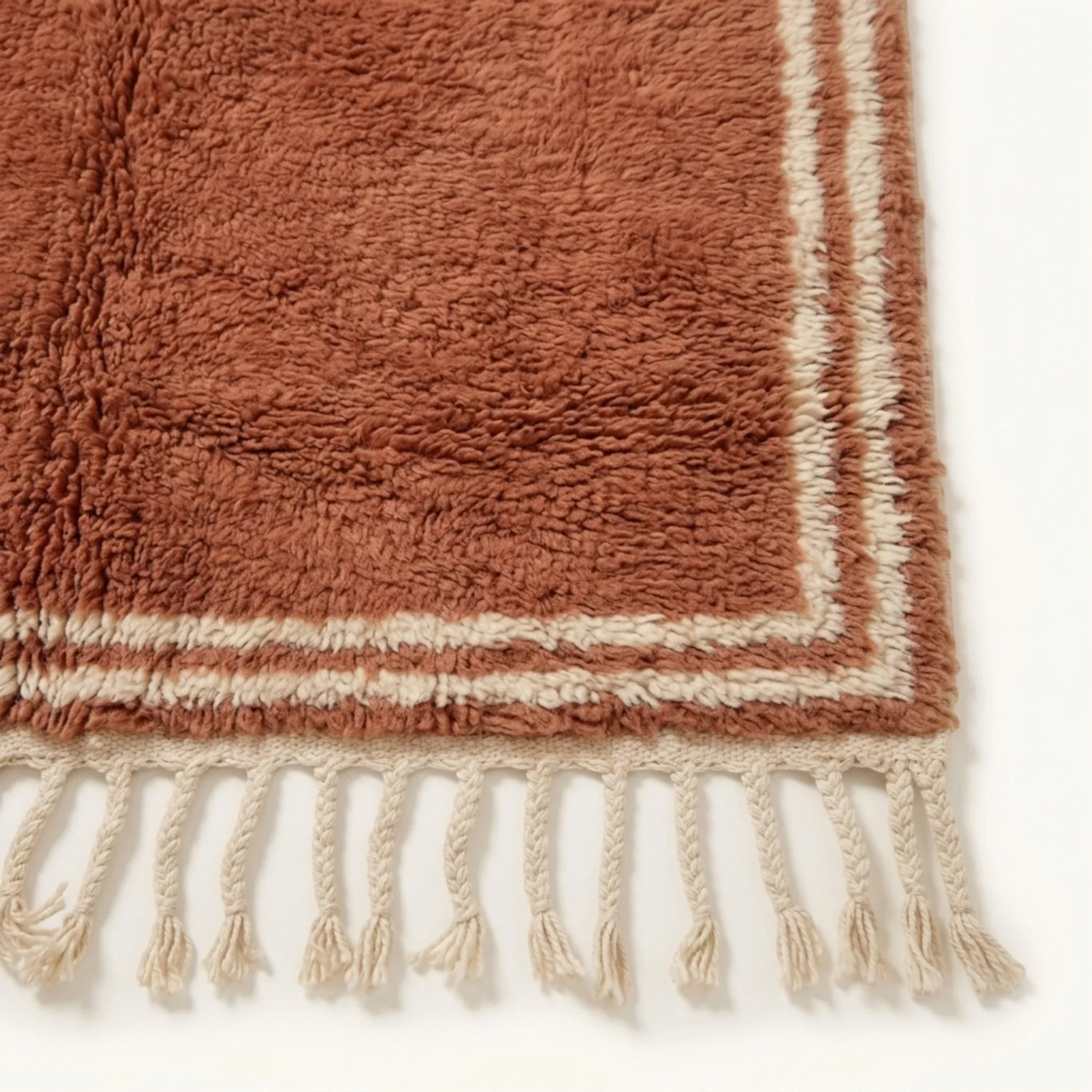 Ivory border and fringe craftsmanship on the Tislit terracotta Beni Ourain rug.