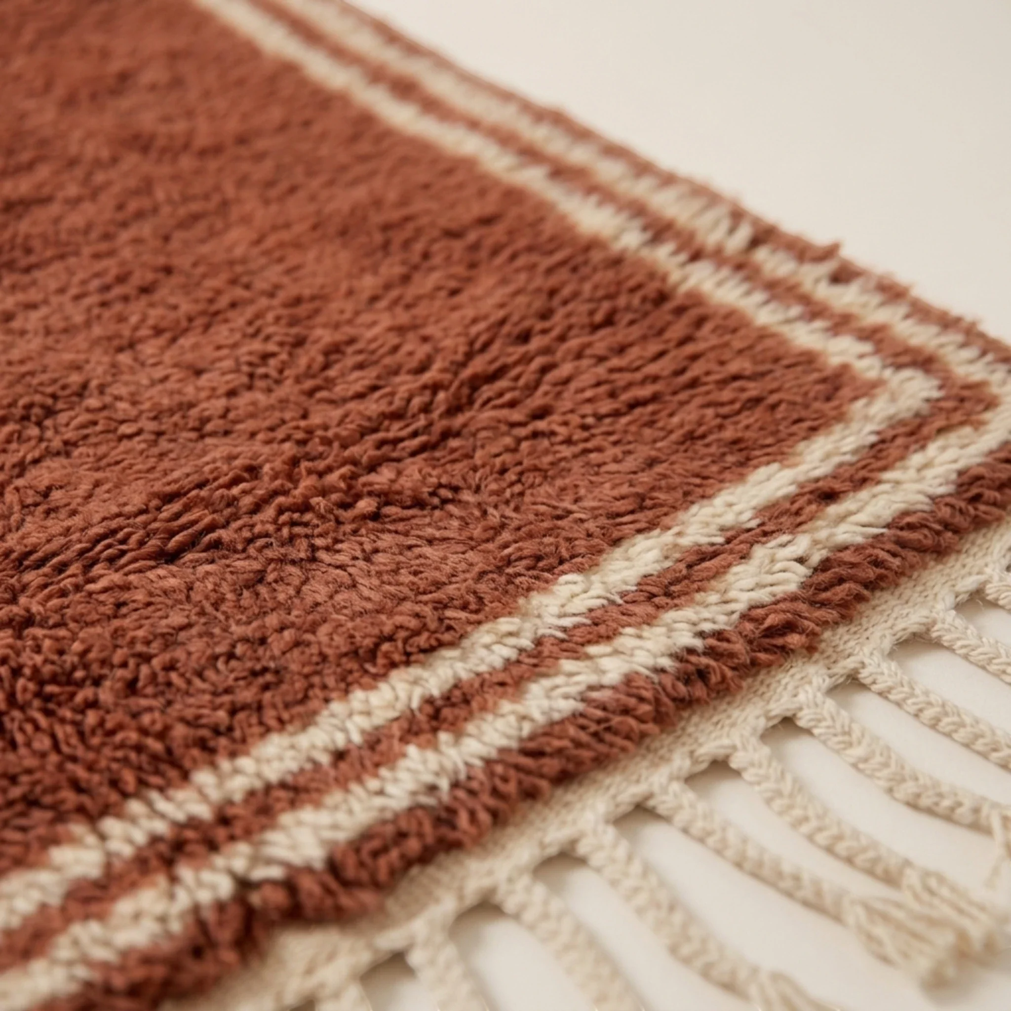 Close-up of the double border texture on the Tislit terracotta and ivory wool rug.