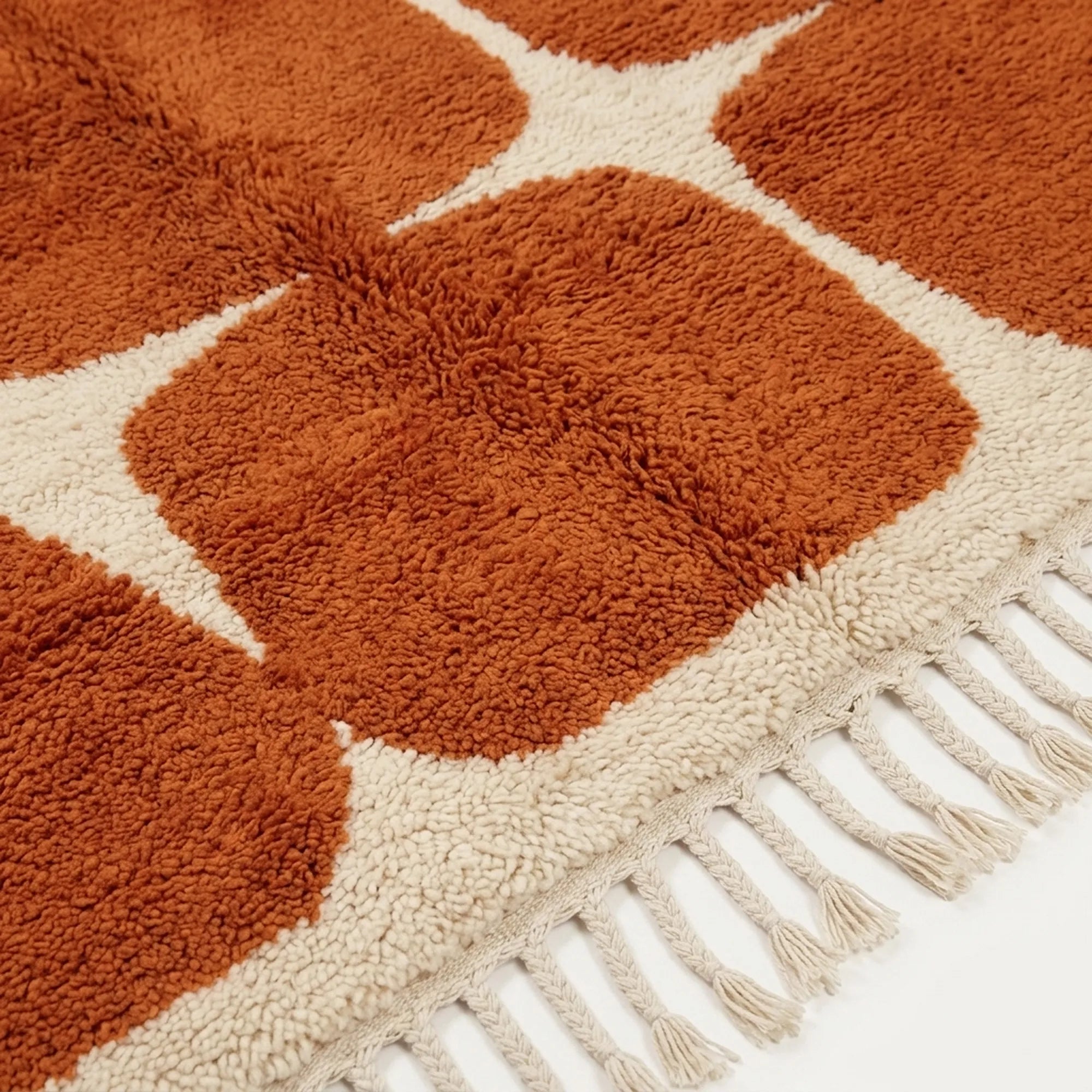 Close-up of the terracotta rounded grid pattern on the Tifawt ivory wool rug.