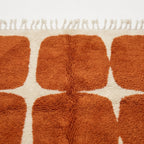 Angled view of the Tifawt terracotta and ivory hand-knotted Beni Ourain rug.