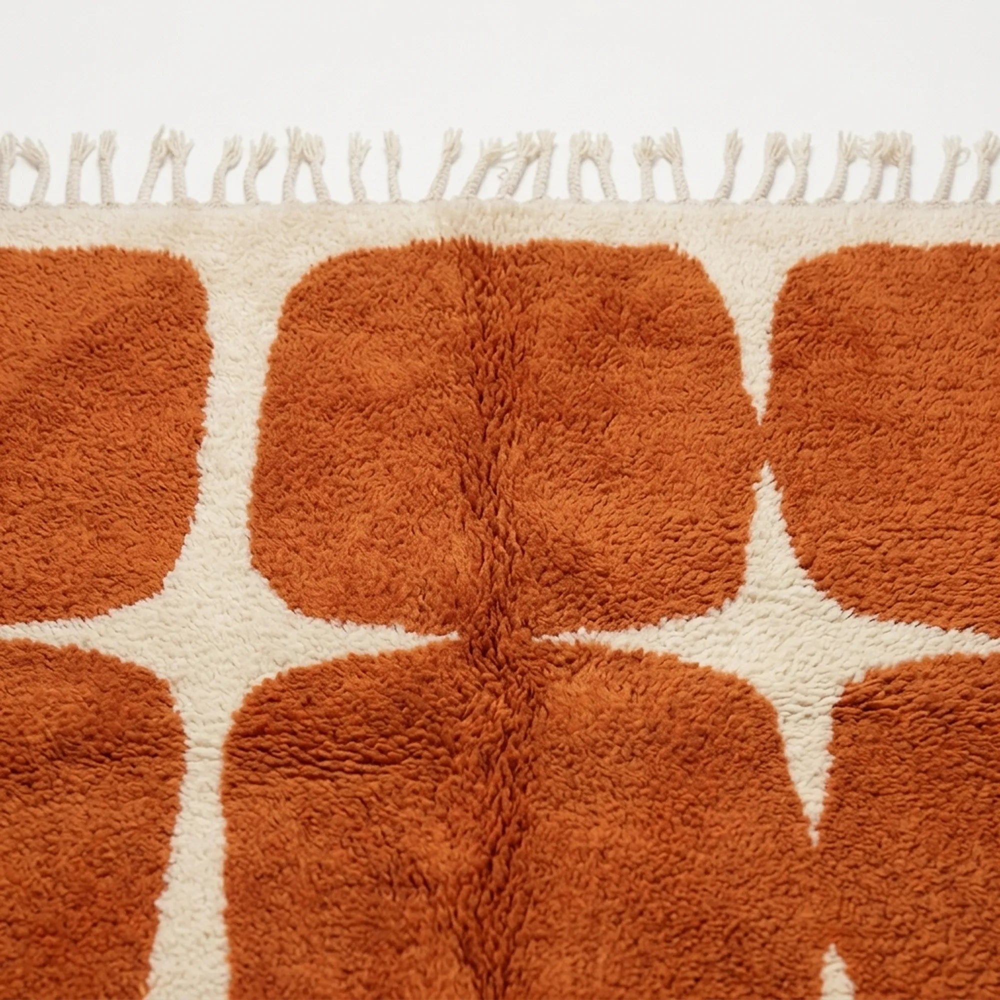 Angled view of the Tifawt terracotta and ivory hand-knotted Beni Ourain rug.