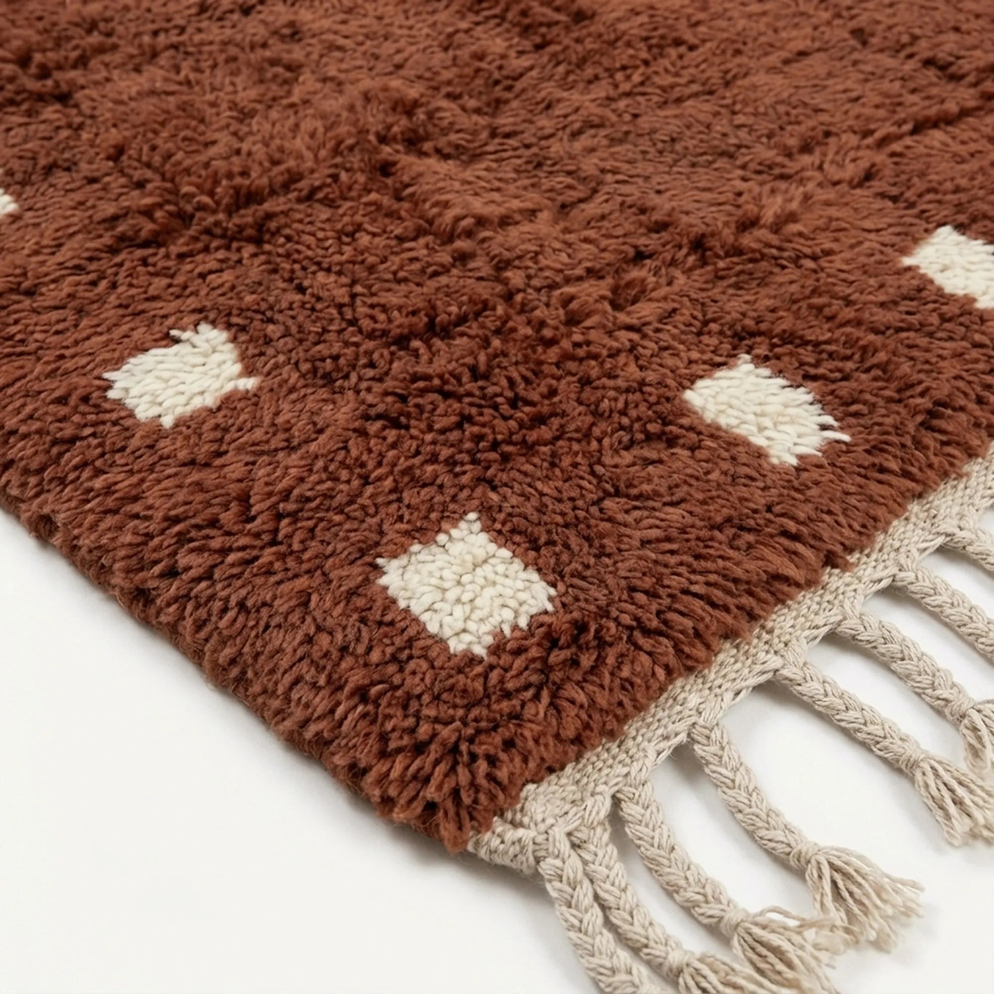 Close-up of the terracotta and ivory wool rug border.
