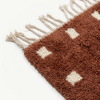 Fringe and border detail of the terracotta and ivory Moroccan wool rug.