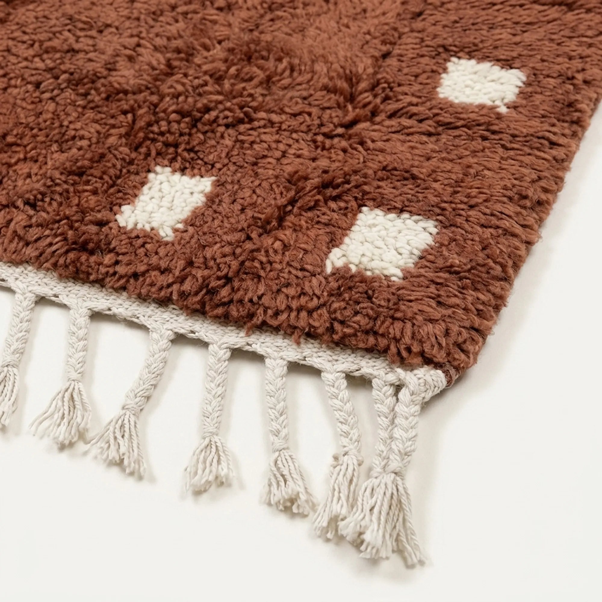 Handmade texture and edge detail of the terracotta and ivory wool rug.