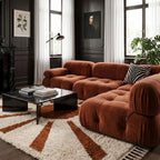 Terracotta and ivory sun-ray rug in modern living room with dark walls, red sofa, and black marble coffee table