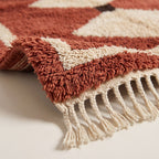 Corner detail showing terracotta border, diamond motif and cream twisted fringe