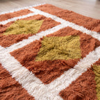 Close-up of chartreuse diamond motif and terracotta pile texture on Mrirt rug