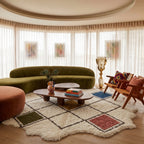 Terracotta, navy, gold, olive and rose diamond lattice Beni Ourain rug in modern living room with curved green sofa and wooden furniture