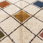 Close-up of thick pile texture showing gold and terracotta diamond centres with dark brown lattice outlines and ivory ground on Beni Ourain rug