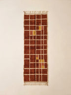 Terracotta, rust and mustard yellow Mrirt runner with cream grid check pattern, shown flat on plain background
