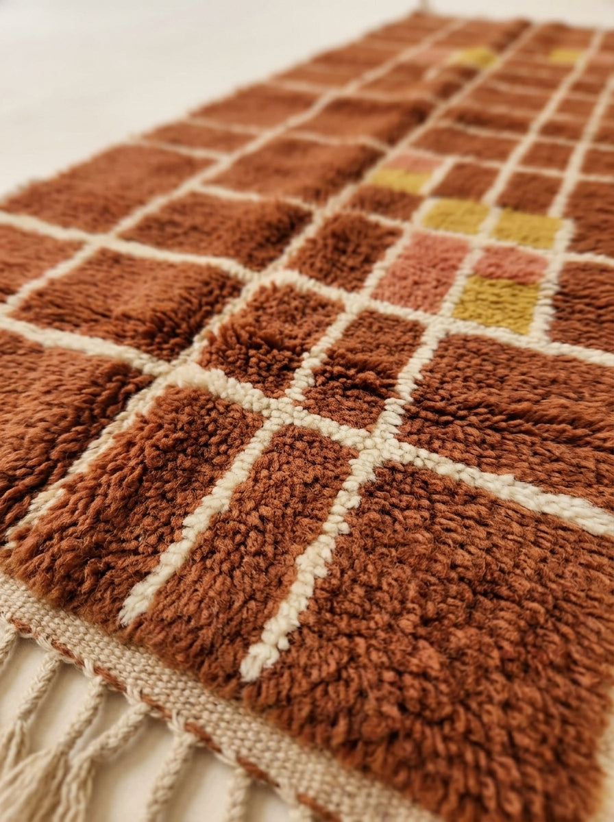 Close-up of plush pile showing terracotta, rust, mustard and cream wool with grid check structure and texture