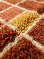 Detailed view of mustard yellow and rust wool squares separated by cream lines in grid check pattern