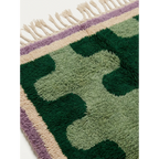 Close-up of the Tifawt rug showing forest-green and sage abstract wool forms.