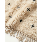 Close-up of the Tislit ivory rug fringe and black cross motifs.