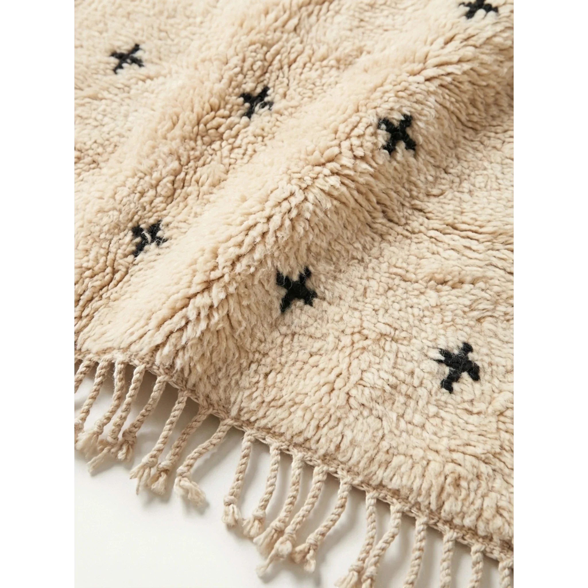 Close-up of the Tislit ivory rug fringe and black cross motifs.